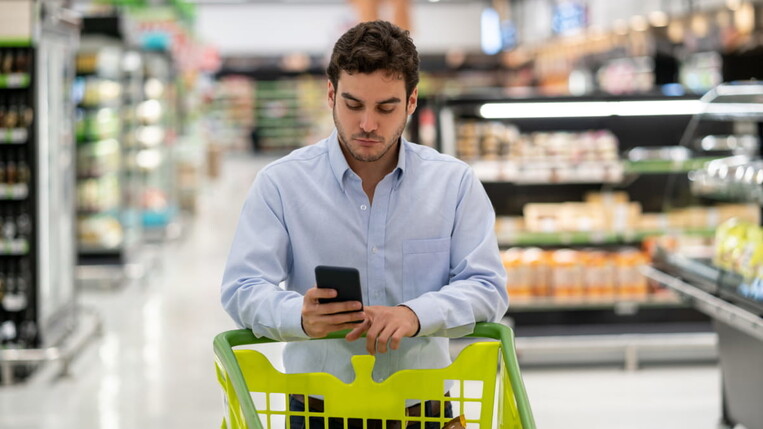 man gets a notification in the grocerie store