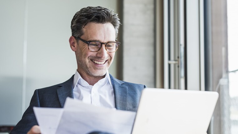 lächelnder Mann vor seinem Laptop