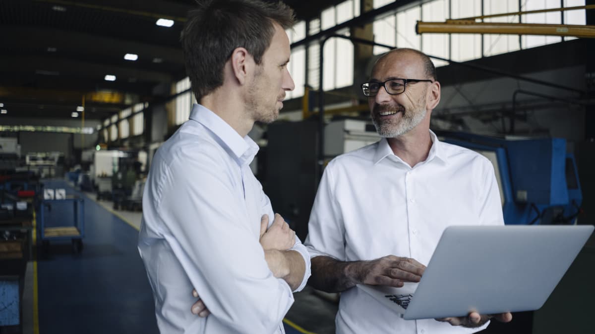 co-workers looking in factory on a laptop