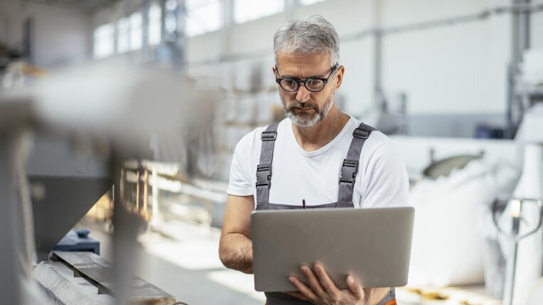 Mann mit Laptop in der Produktion