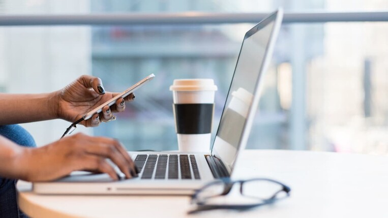 Marketing manager using marketing tools on phone and laptop